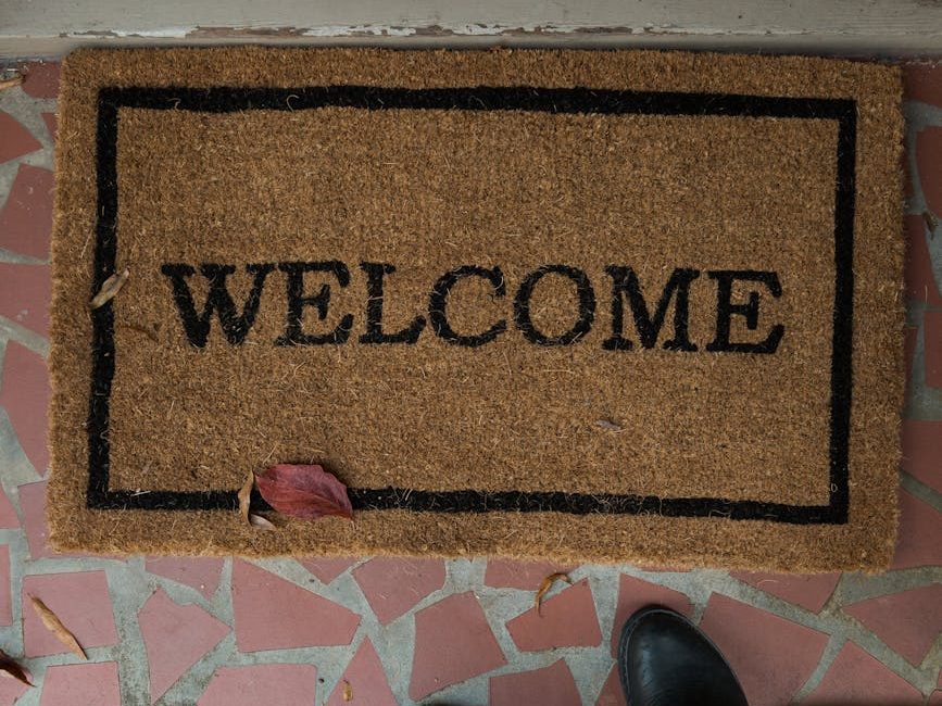 person wearing black shoes standing near a doormat